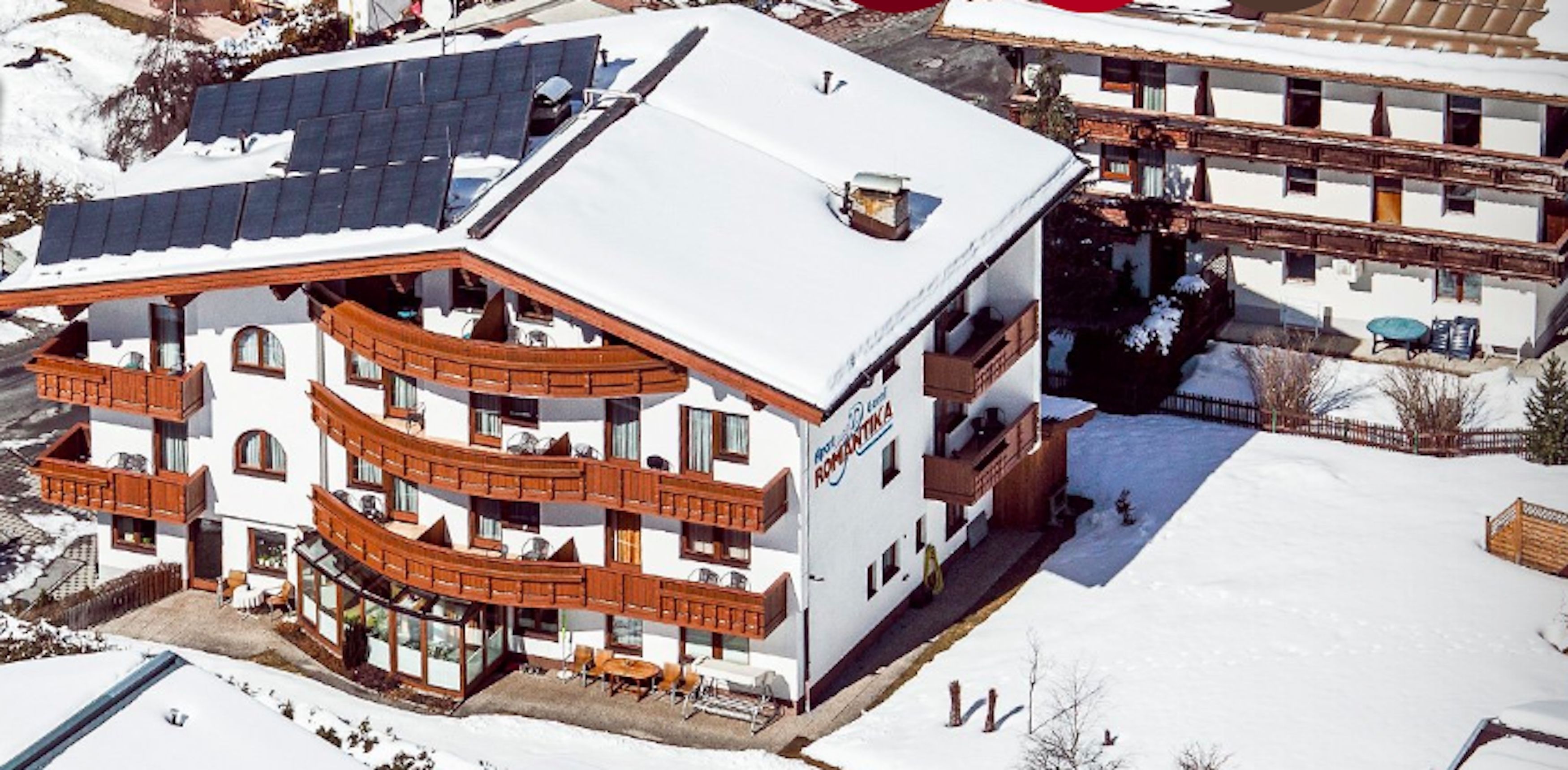 A multi-story hotel with balconies, a ski slope, and a snow-covered landscape.