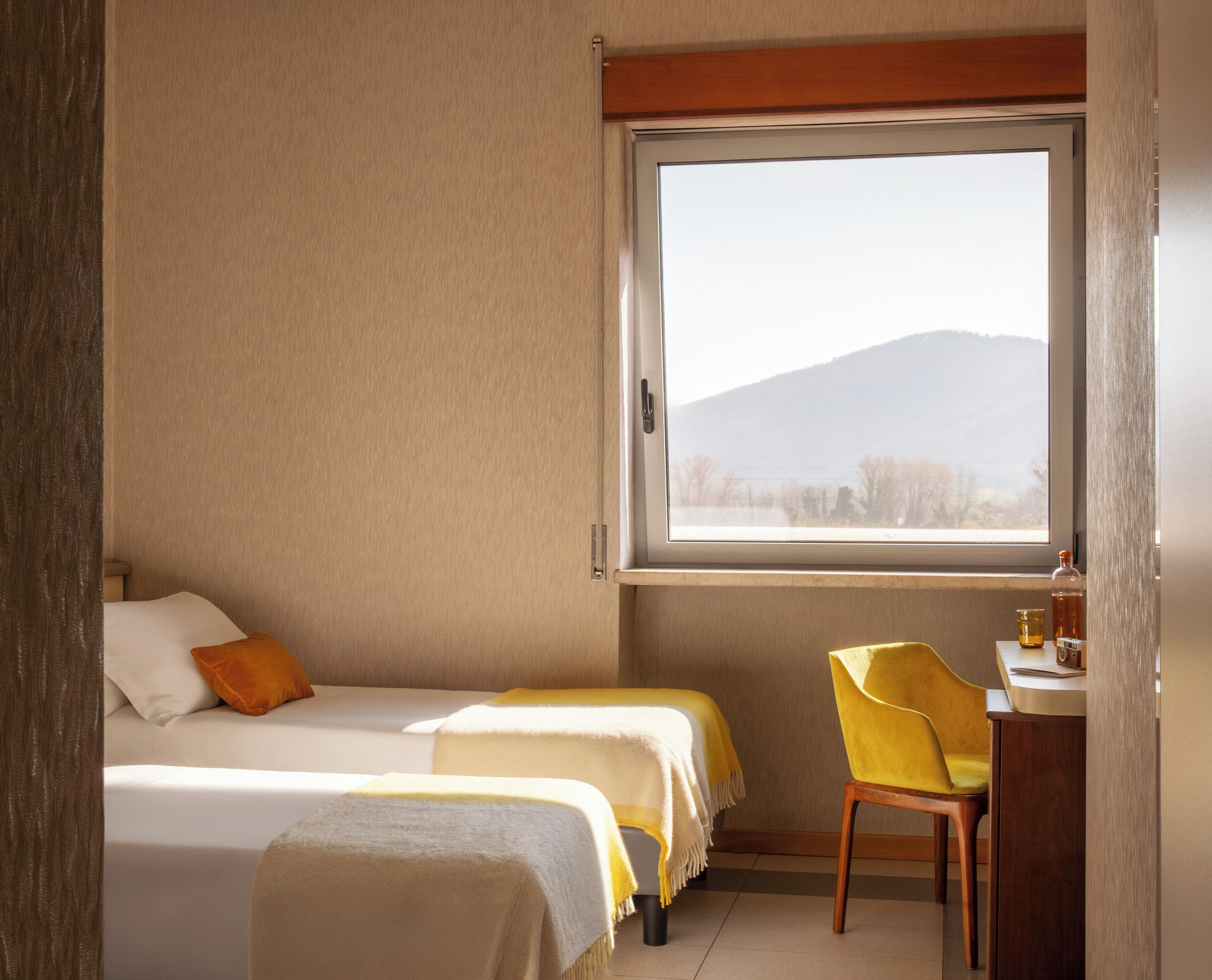 Una habitación con dos camas, un escritorio y una ventana con vistas a la montaña.