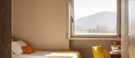 Una habitación con dos camas, un escritorio y una ventana con vistas a la montaña.