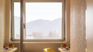 A room with a bed, two chairs, a desk, a window with a view of mountains, and a door. - Hotel Al Sant andrea (Sarzana)