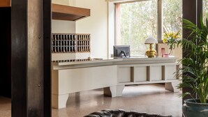 A modern kitchen with a white countertop, a black leather chair, and a large window with a view of trees. - Hotel Al Sant andrea (Sarzana)