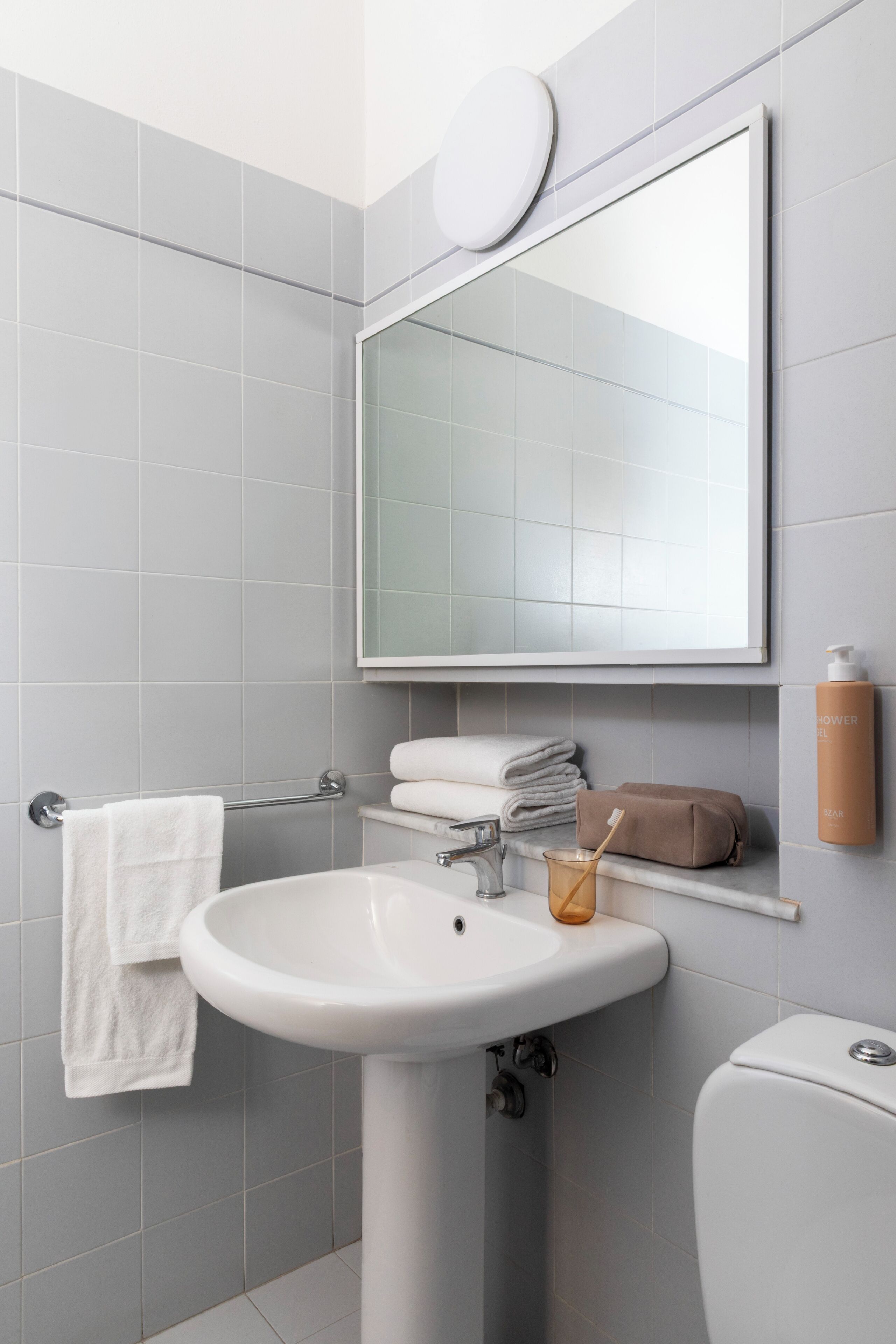 A bathroom with a white sink, a mirror, a toilet, and a towel rack.