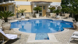 Una piscina con sillas de descanso y plantas en macetas.