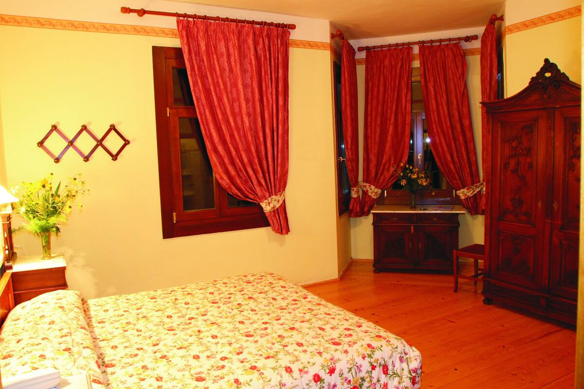 A bedroom with a bed, a wooden desk, and a wardrobe.