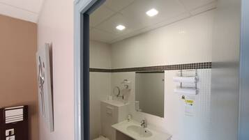 A bathroom with a toilet, sink, mirror, and towel rack.