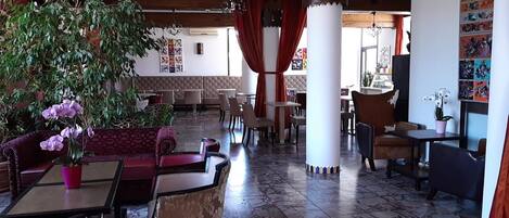 Ein Restaurant mit einer roten Couch, einem Tisch mit einem Topfblumen und einer Sitzecke.