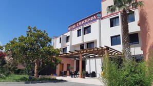 A hotel named "Hotel Hacienda" with a covered outdoor seating area and a palm tree. - Hôtel l'Hacienda (Chateauneuf-les-Martigues)