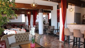 A restaurant with a bar area, leather seating, and a decorative vase with flowers. - Hôtel l'Hacienda (Chateauneuf-les-Martigues)
