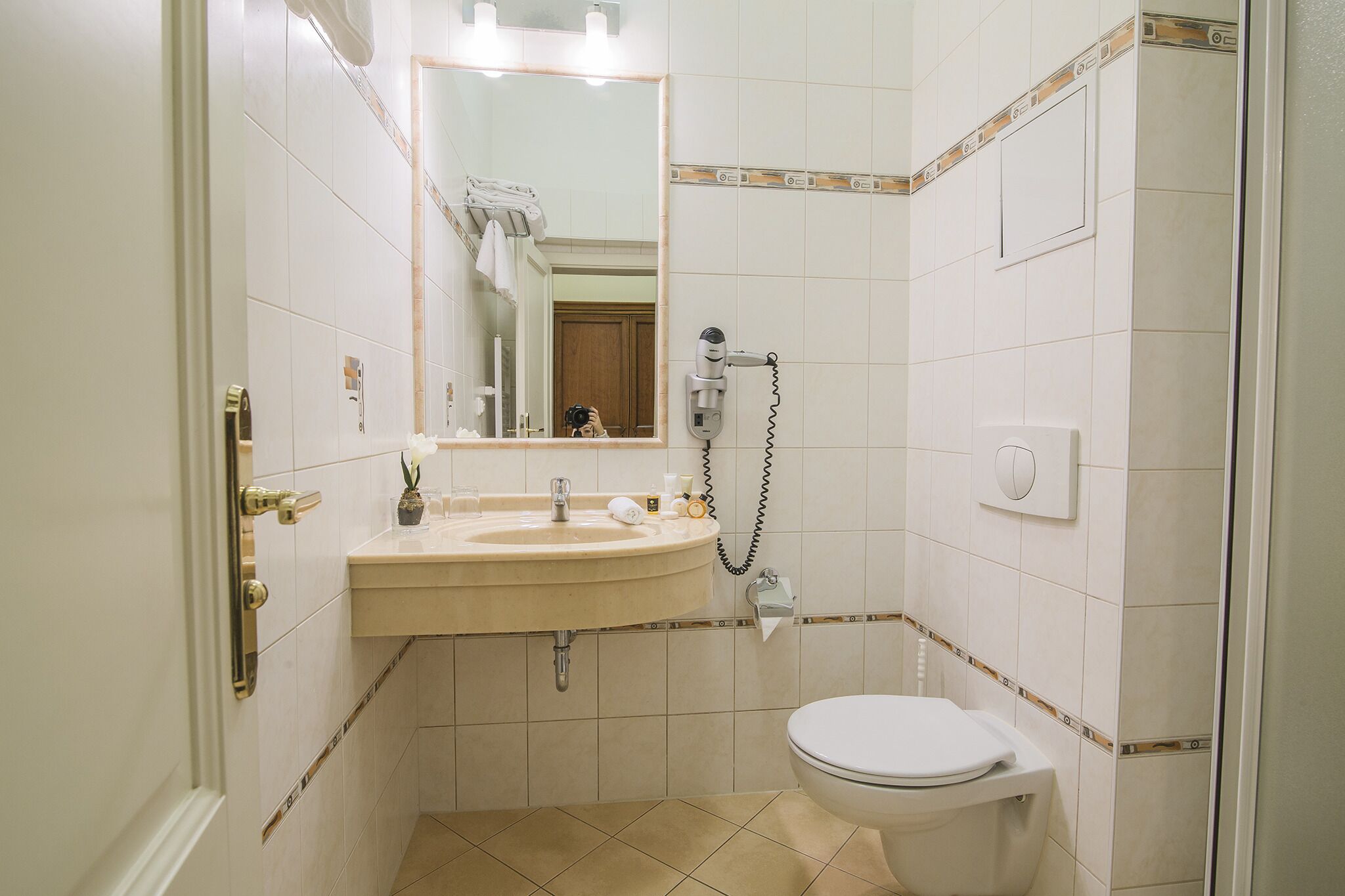 A small bathroom with a sink, mirror, and toilet.