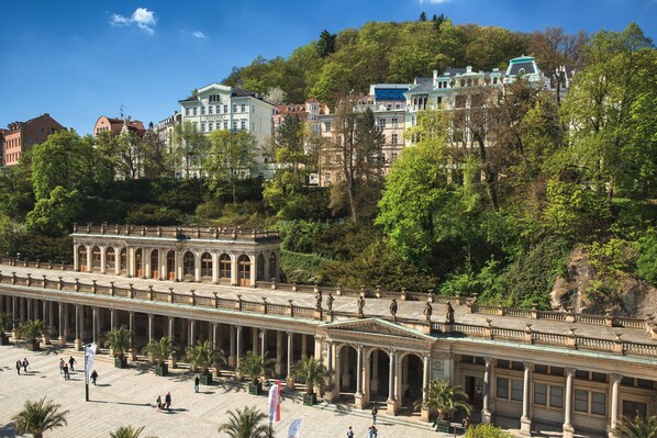 Un bâtiment de style classique, doté d’une longue colonnade, entouré d’une végétation luxuriante et d’autres monuments historiques.