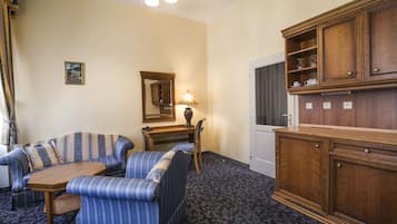 A room with a sofa, a small table, a lamp, a mirror, and wooden cabinets.