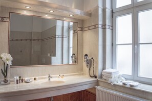 Une salle de bain avec un grand miroir, un lavabo, un sèche-cheveux et des serviettes.