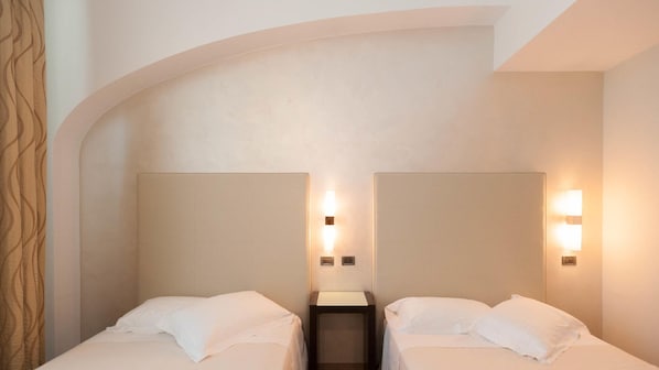 A hotel room with two beds, a small bedside table, and wall-mounted lights. - Hotel La Cartiera (Vignola)