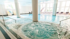 An indoor swimming pool with a hot tub area, lounge chairs, and large windows. - Hotel La Cartiera (Vignola)