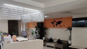 A reception area with a desk, seating, a world map on the wall, and a decorative hanging light fixture. - Hotel La Cartiera (Vignola)
