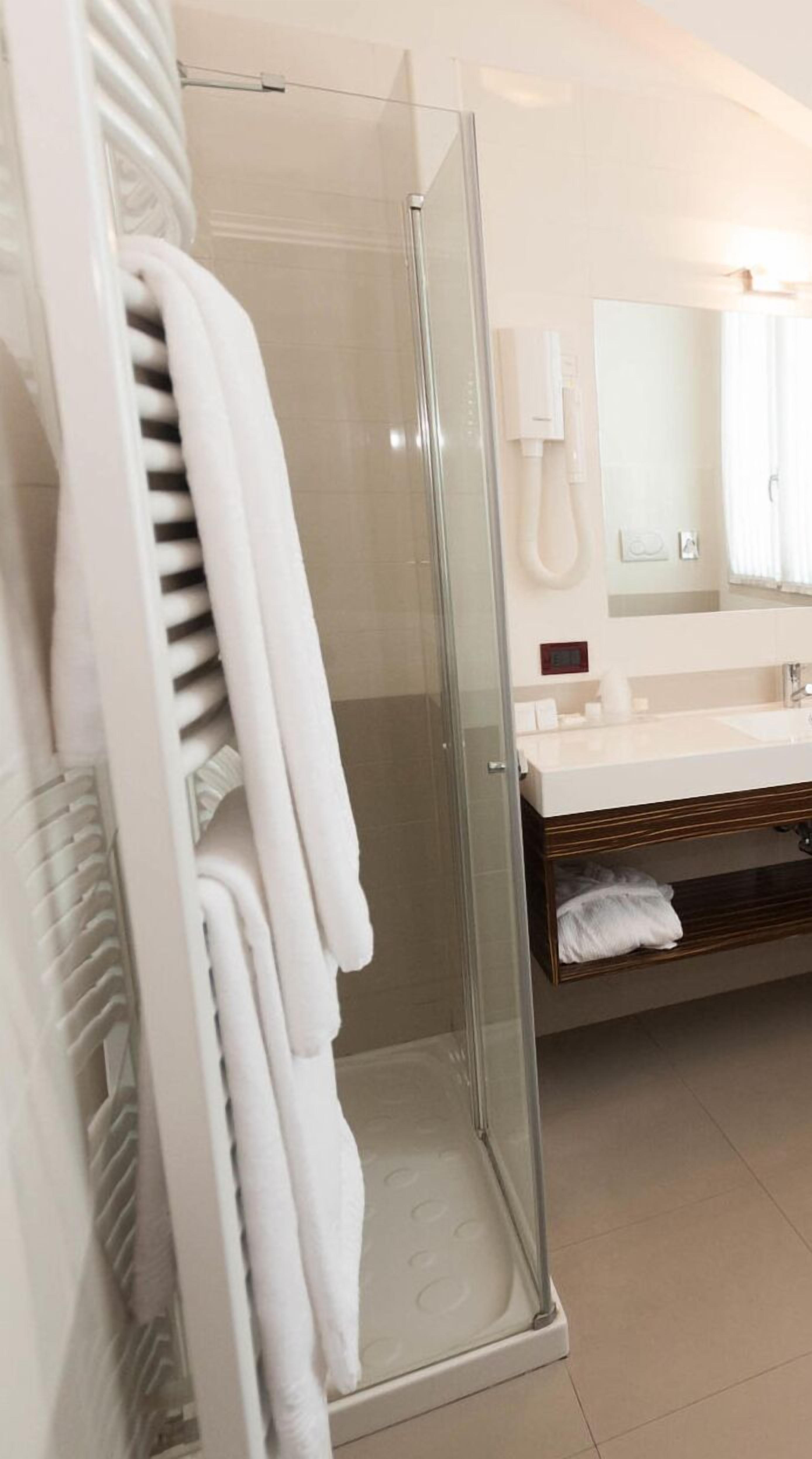 A modern bathroom with a glass-enclosed shower, a white sink, and a towel rack with folded towels.