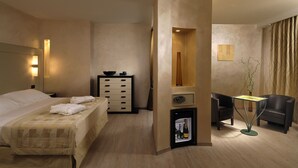 A hotel room with a bed, a dresser, a small table with a vase, and two chairs. - Hotel La Cartiera (Vignola)