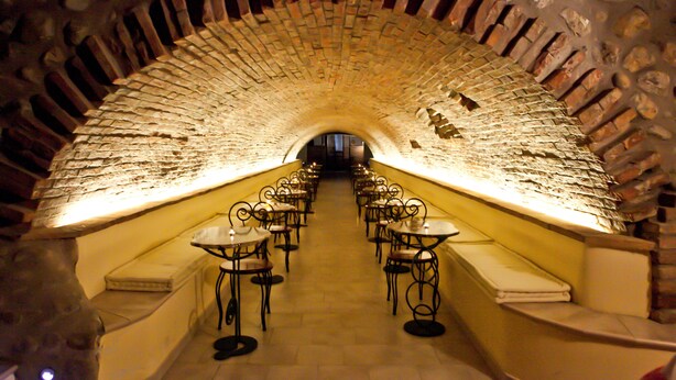 A long, arched brick tunnel with tables and chairs arranged along the sides. - Hotel La Cartiera (Vignola)