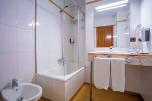 Un baño moderno con cabina de ducha de vidrio, lavabo y espejo.