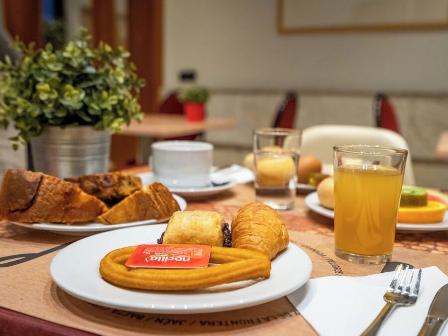 Una mesa de comedor con platos de comida, incluyendo pasteles y un vaso de jugo.