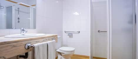 A modern bathroom with a glass shower enclosure, a white toilet, and a sink with a marble countertop.