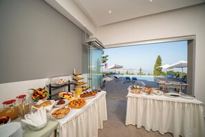 A buffet setup with various food items and a pool view. - Panoramic Sunset (Kefalonia)