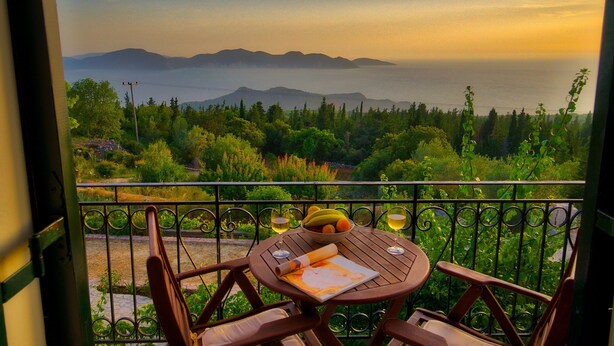 A balcony with a table set for two, overlooking a mountainous landscape. - Panoramic Sunset (Kefalonia)