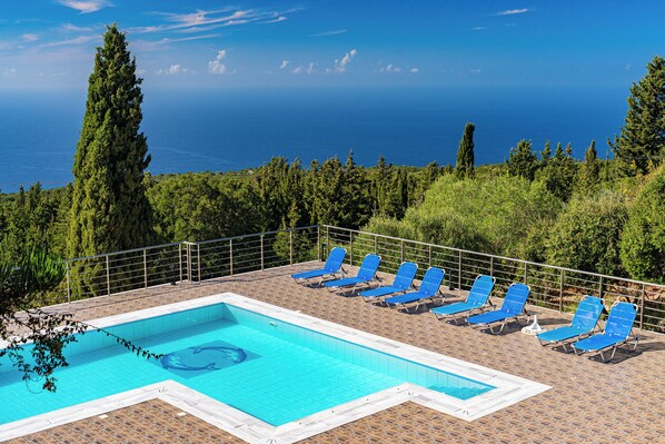 En säsongsöppen utomhuspool, parasoller och solstolar