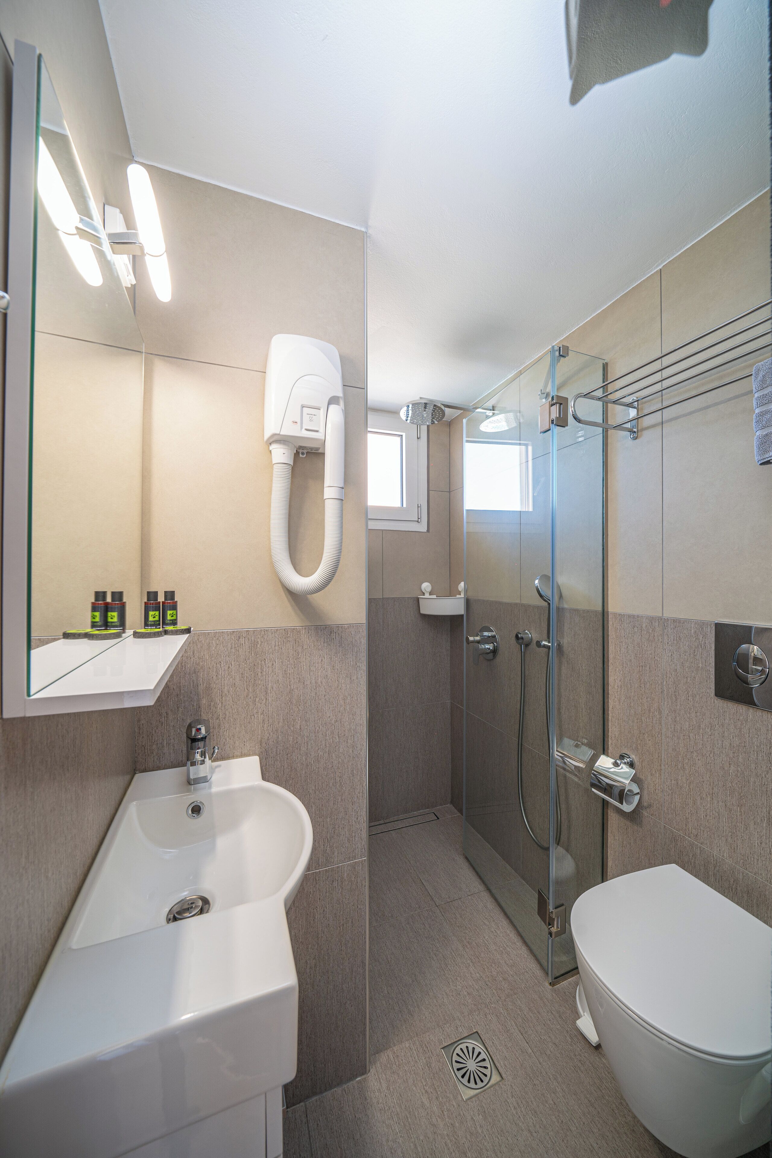 Un baño moderno con cabina de ducha de vidrio, lavabo blanco y retrete.