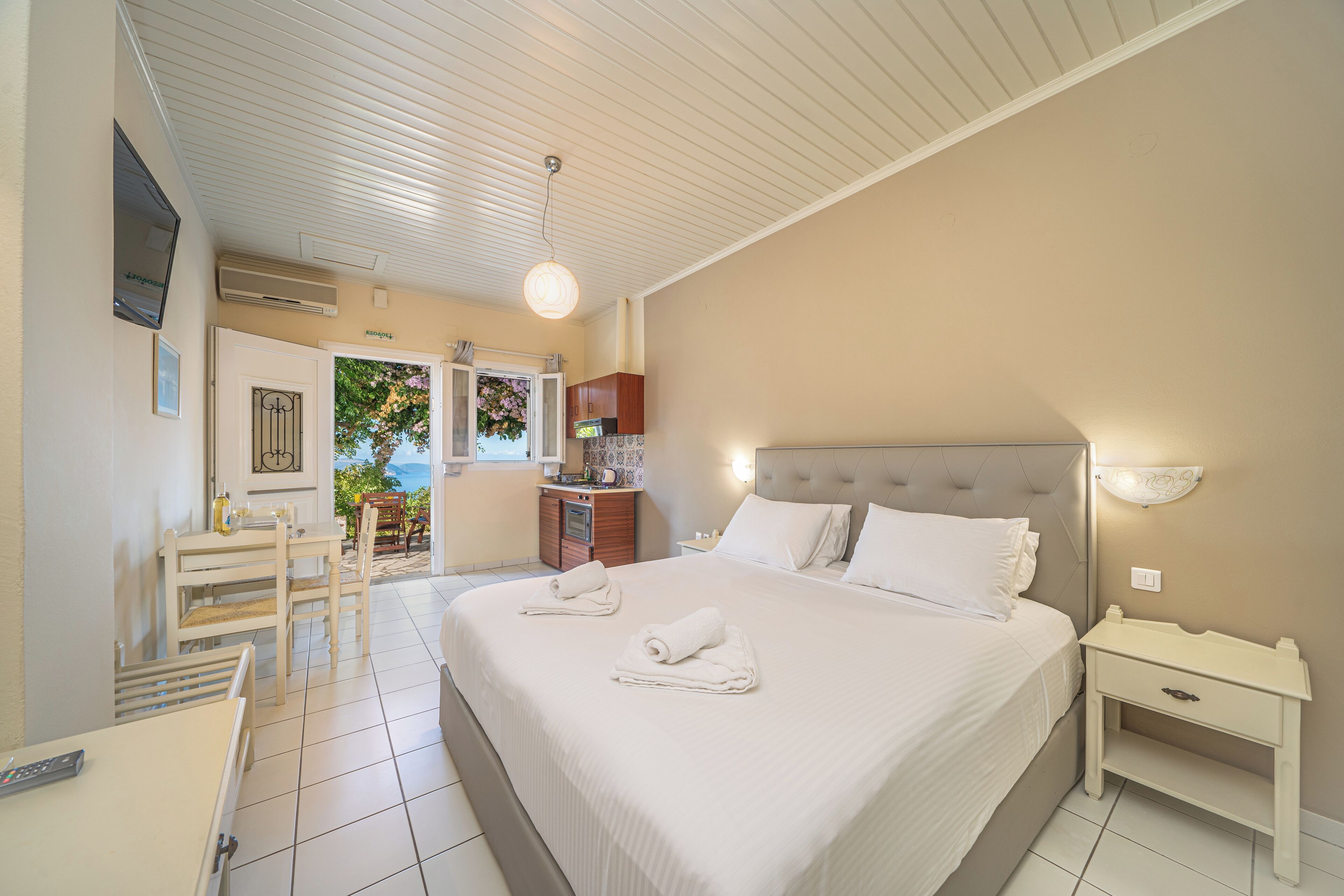 A bedroom with a large bed, bedside table, and a small desk with a chair.