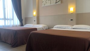 A hotel room with two beds, each with a brown bedspread and white pillows. There are wall-mounted light fixtures on either side of the beds, and a painting of flowers above them. - Hotel Indipendenza (Rome)