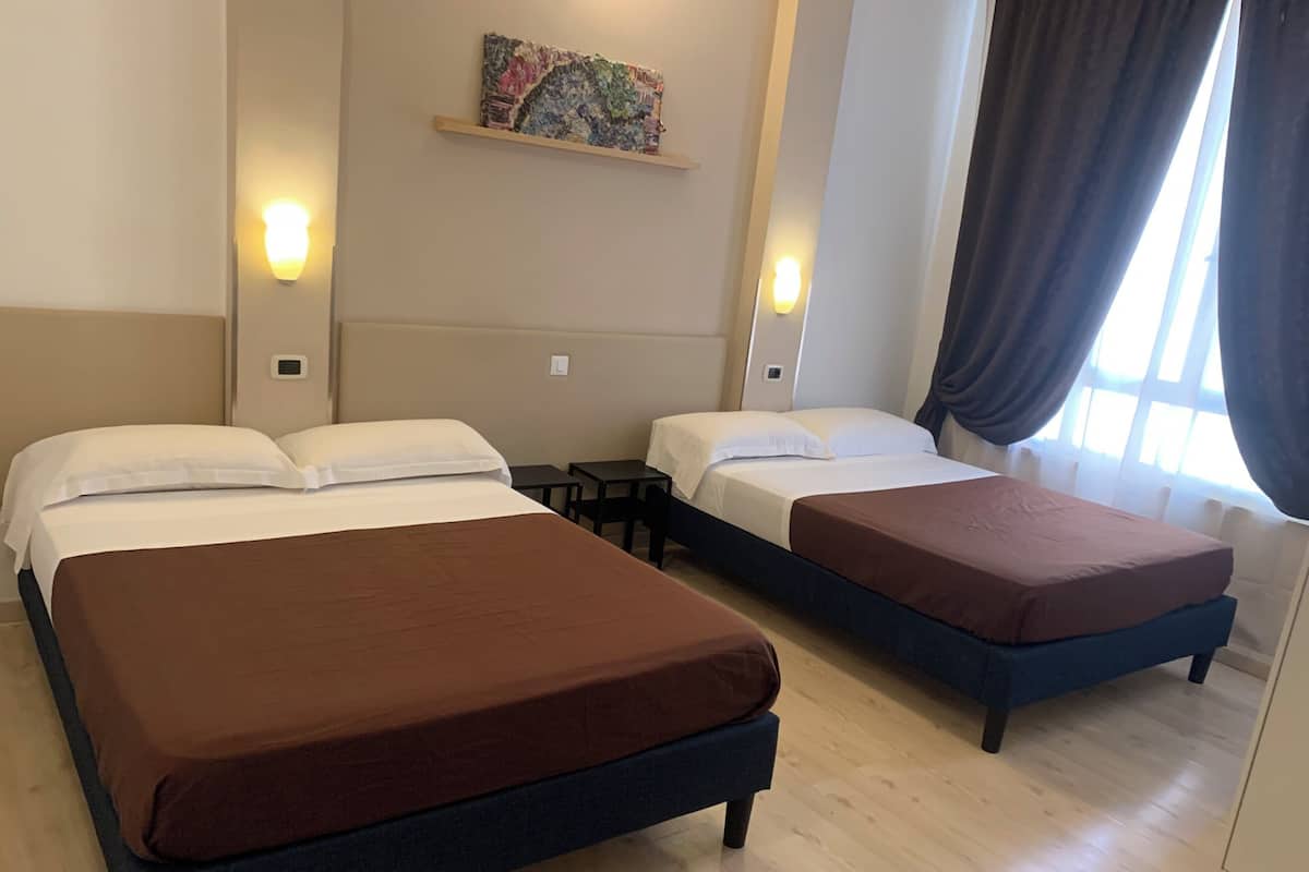 A hotel room with two beds, a small table, and a painting on the wall.