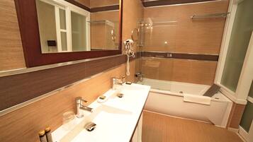 Un baño moderno con un espejo grande, dos lavamanos, una bañera y una ducha.