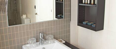 A bathroom with a white sink, a mirror, and a dark wooden cabinet above it.
