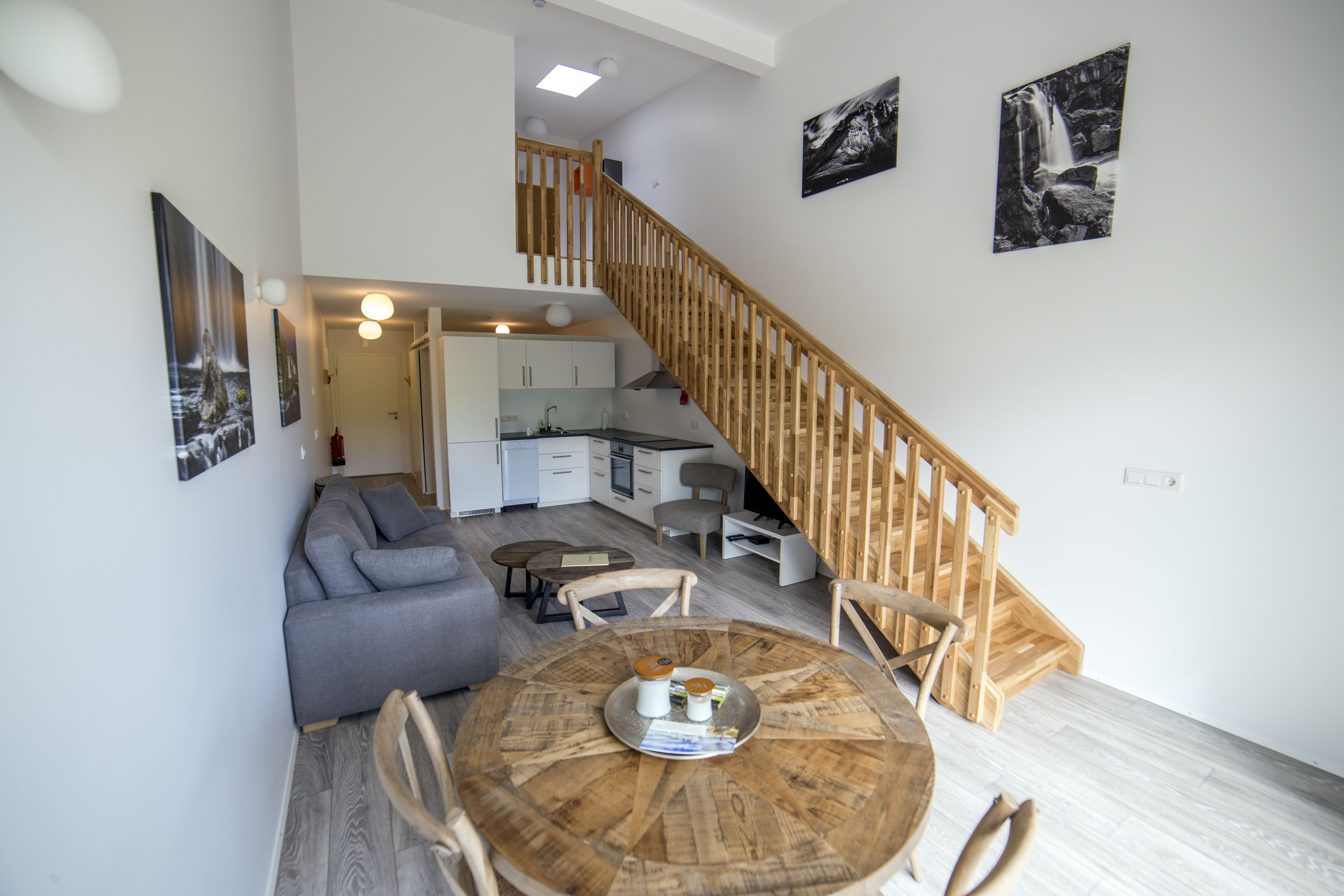 A modern living space with a dining area, kitchen, and staircase.