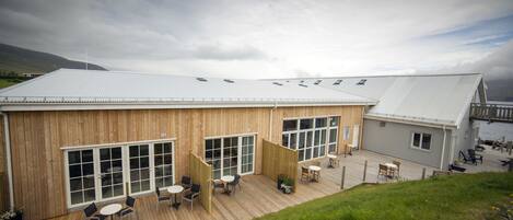 A wooden building with large windows and a deck area with outdoor seating.