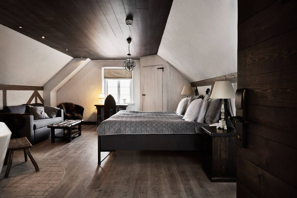 A bedroom with a large bed, a desk, a chair, and a sofa.