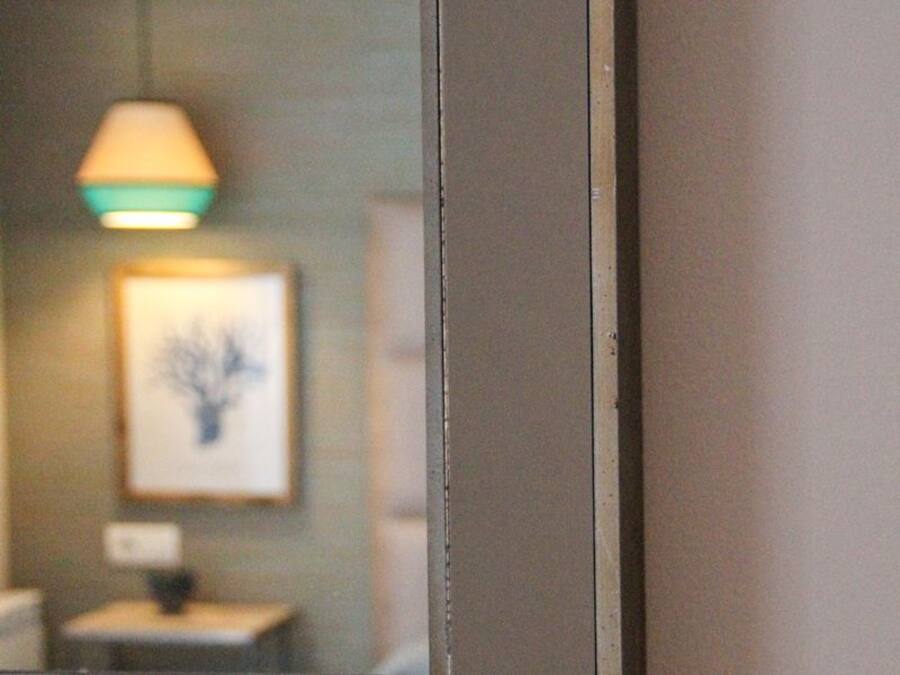 A mirror reflecting a bathroom interior with a framed picture on the wall.