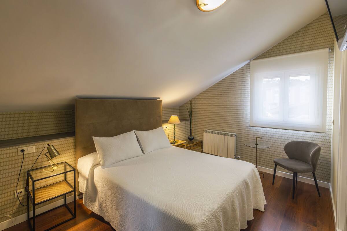 Un dormitorio con cama, una silla, una mesita de noche, una lámpara y un radiador.