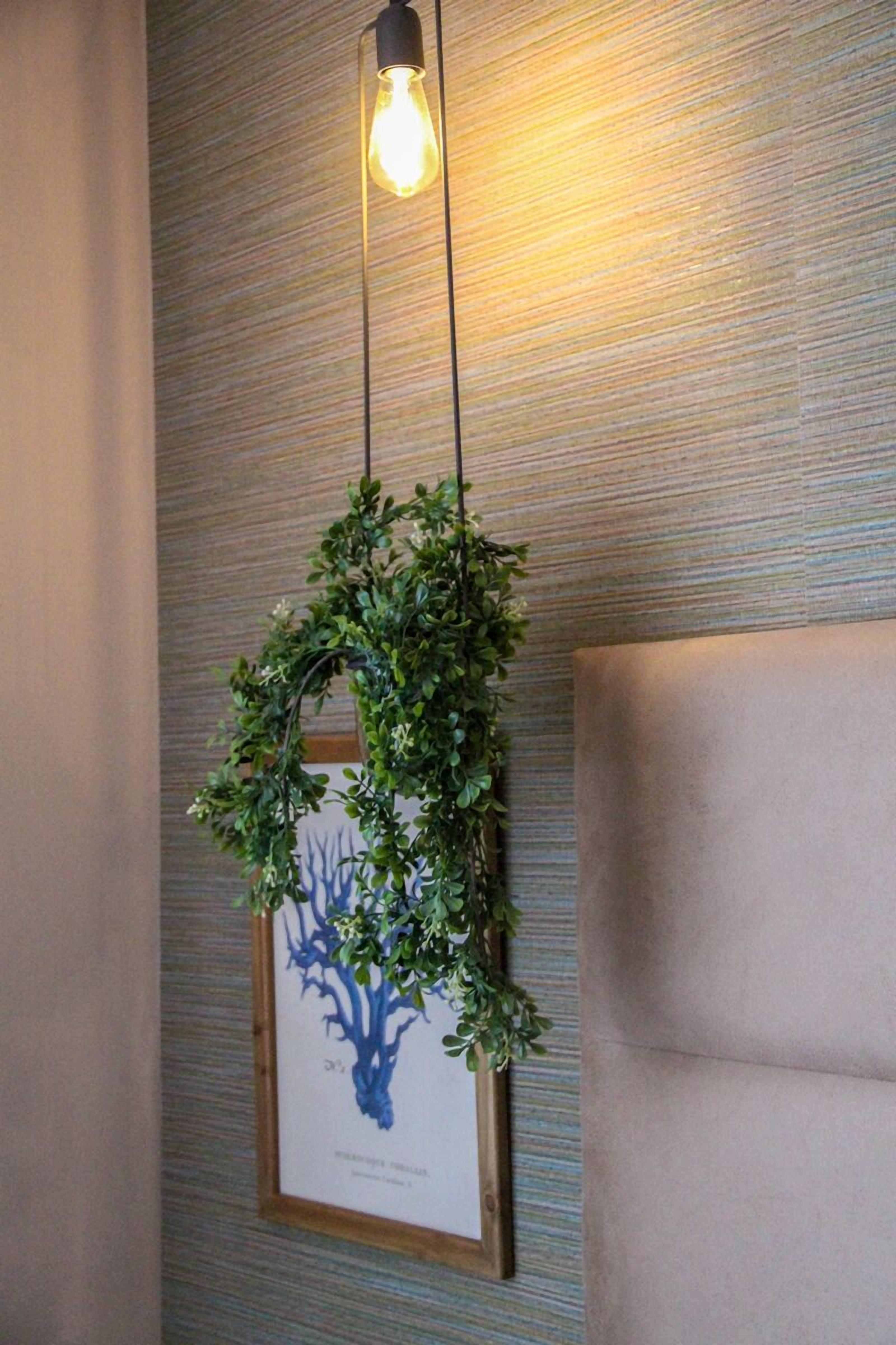 A framed botanical print hanging on a textured wall, with a hanging light fixture above it.