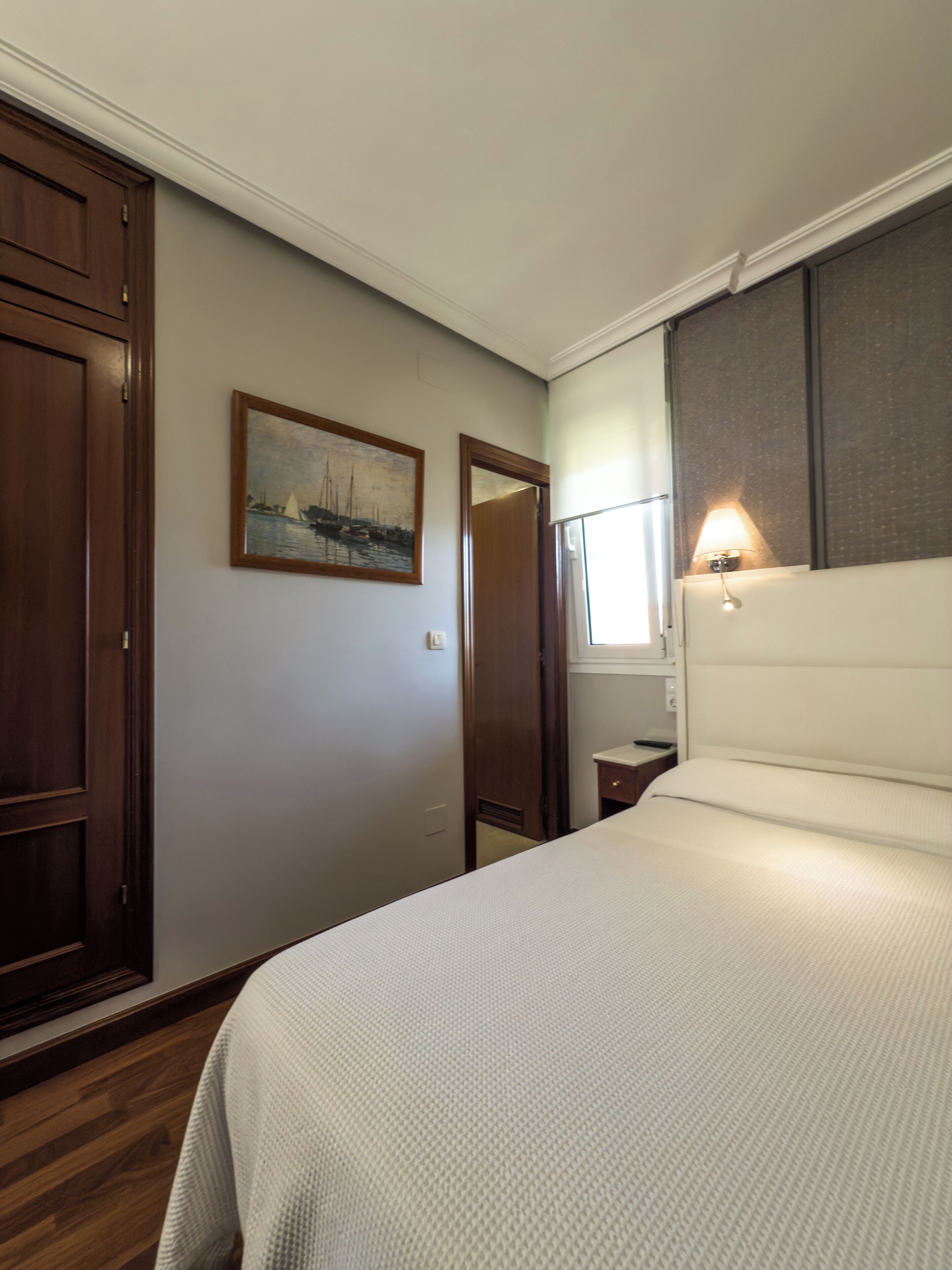 Une chambre à coucher avec un lit, une table de chevet, une lampe, un tableau et une armoire.