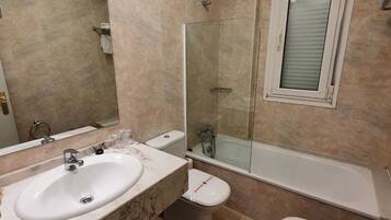 A bathroom with two sinks, a toilet, a bathtub, and a shower enclosure.