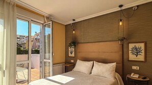 Un dormitorio espacioso con una cama grande, cabecera de madera, mesita de noche con lámpara y vistas a un espacio exterior a través de un ventanal corredero.