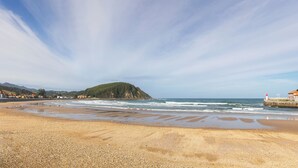 Una playa con piedras, un faro y un edificio con techo rojo.