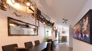 A dining area with a long table, chairs, and a unique chandelier.