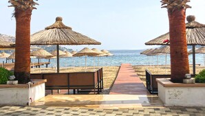 A pathway leading to beach umbrellas and a beach view. - Butikhan Otel (Bodrum)