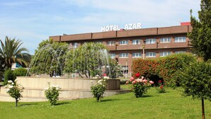 Un hotel llamado HOTEL AZAR con un jardín y una fuente.