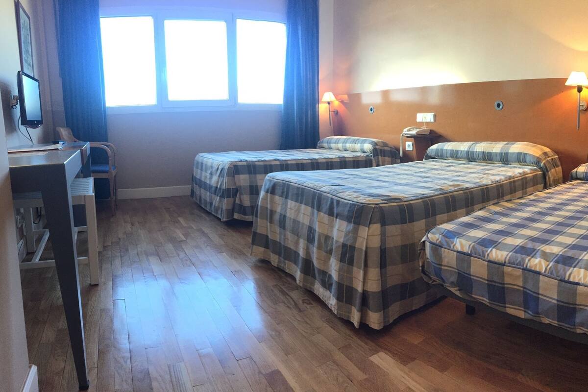 Habitación de hotel con dos camas, un escritorio y una computadora.