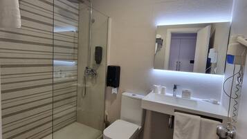 Une salle de bain moderne avec une douche à parois de verre, des toilettes blanches, un lavabo avec un miroir et un porte-serviettes.