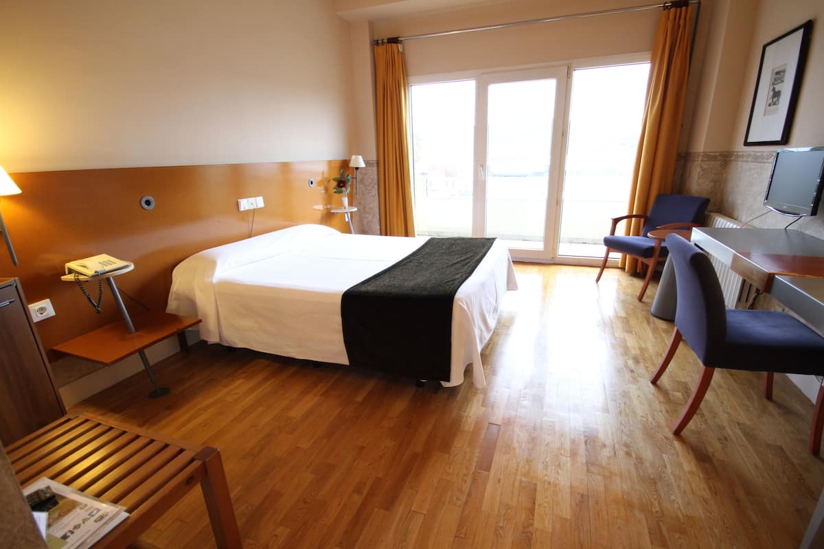 Una habitación de hotel con cama, escritorio, sillas y vistas al exterior.